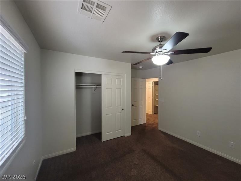 A spacious bedroom features plush carpeting, a reach-in closet, and a large window.