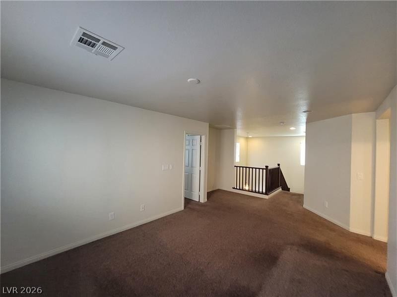 A spacious upper-level loft features wall-to-wall carpeting and access to the staircase.