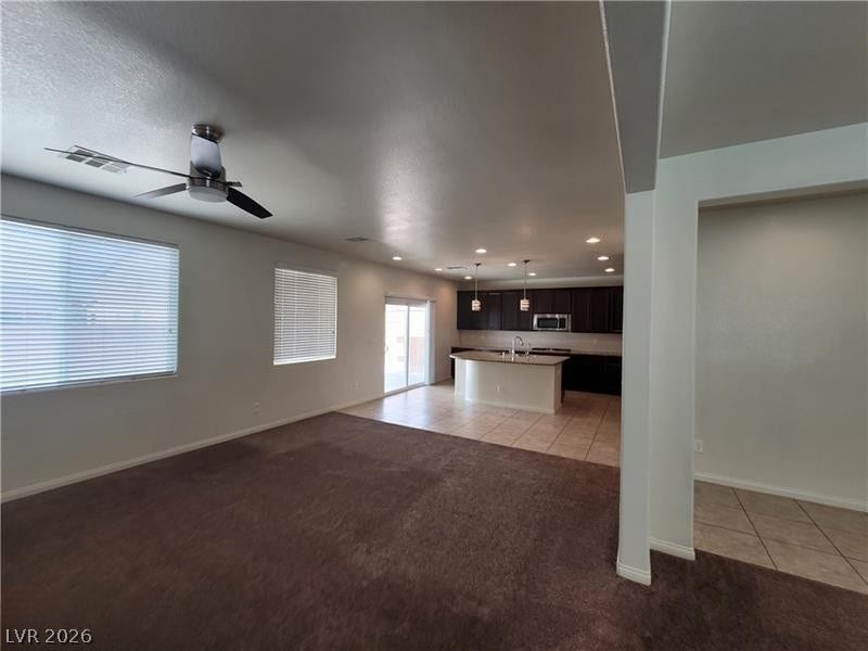 An open floor plan seamlessly connects the carpeted living area to the tiled kitchen.