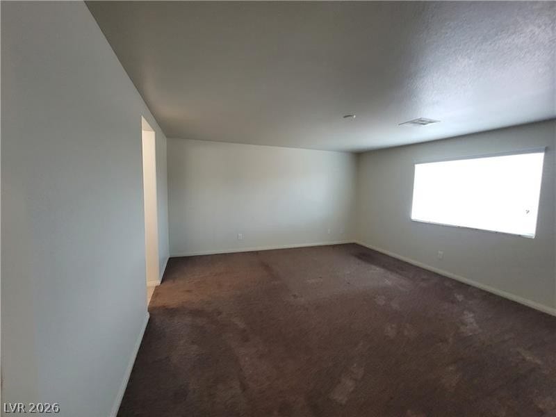 A spacious room features plush carpeting and a large window providing ample natural light.