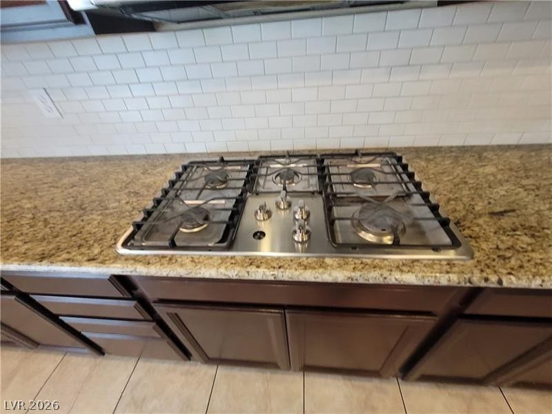 Granite countertops and a classic subway tile backsplash surround the gas cooktop.