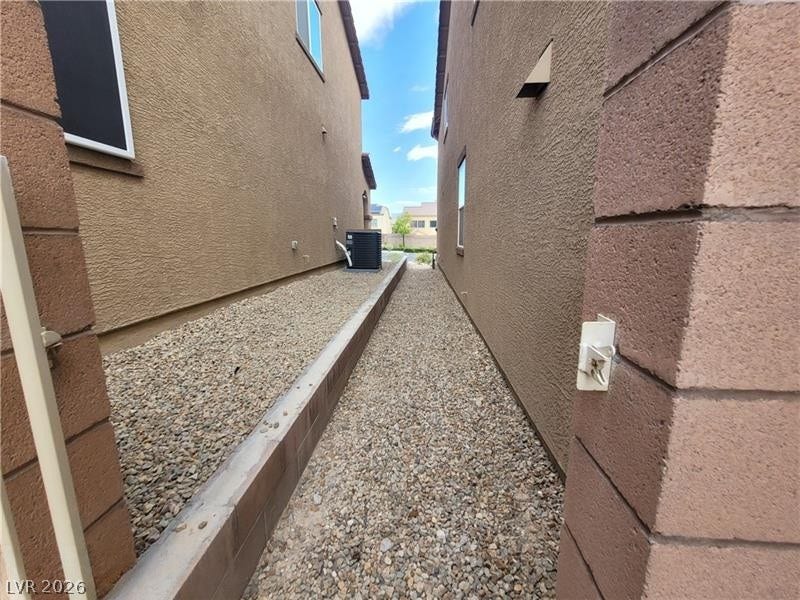 A gravel-lined side yard walkway connects the properties under clear desert skies.