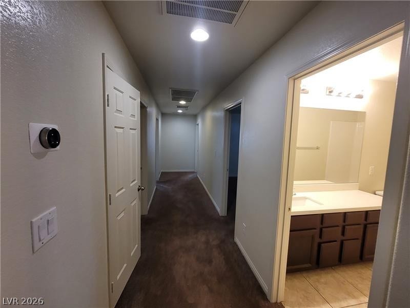A long hallway connects private rooms to an adjoining bathroom with tile flooring.