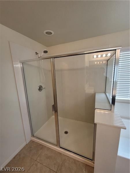A glass-enclosed shower with tile flooring anchors this modern bathroom space.