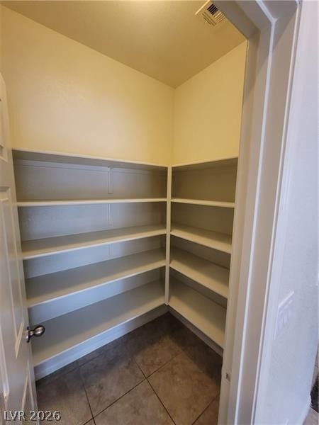 A walk-in pantry provides wrap-around shelving and durable tile flooring.