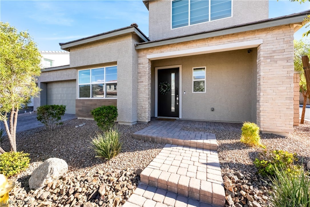 10143 Bismarck Palms Avenue, Las Vegas, NV 89166 A welcoming stone-accented entryway leads past low-maintenance desert landscaping to the front door.