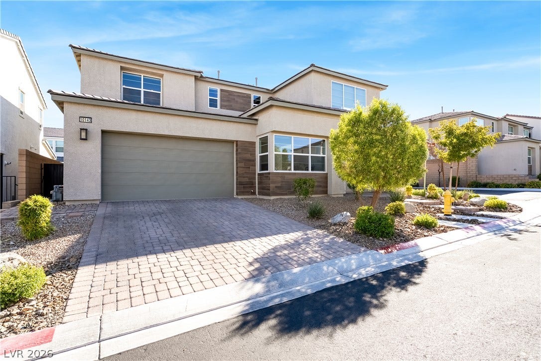 10143 Bismarck Palms Avenue, Las Vegas, NV 89166 A paved driveway leads to a modern two-story home featuring clean stucco and wood-panel accents.