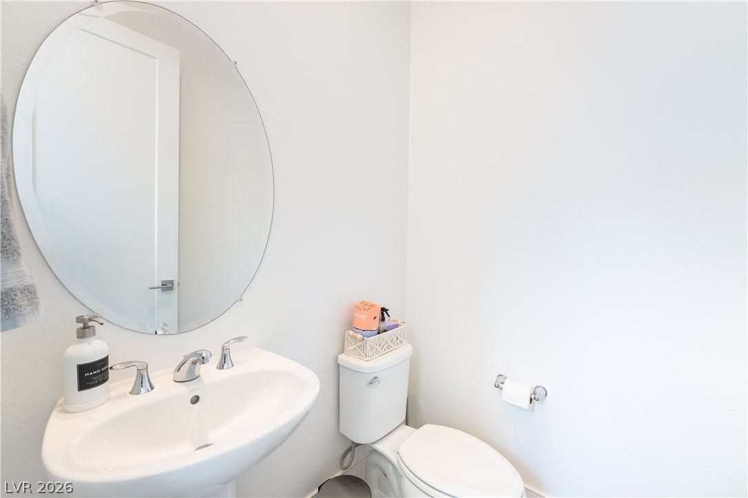 10143 Bismarck Palms Avenue, Las Vegas, NV 89166 A clean pedestal sink and round mirror define this minimalist half bath.