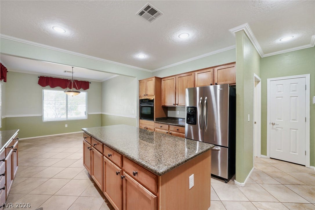 7421 Shelduck Street, North Las Vegas, NV 89084 Gleaming stone countertops and classic wood cabinetry enrich this open culinary space.