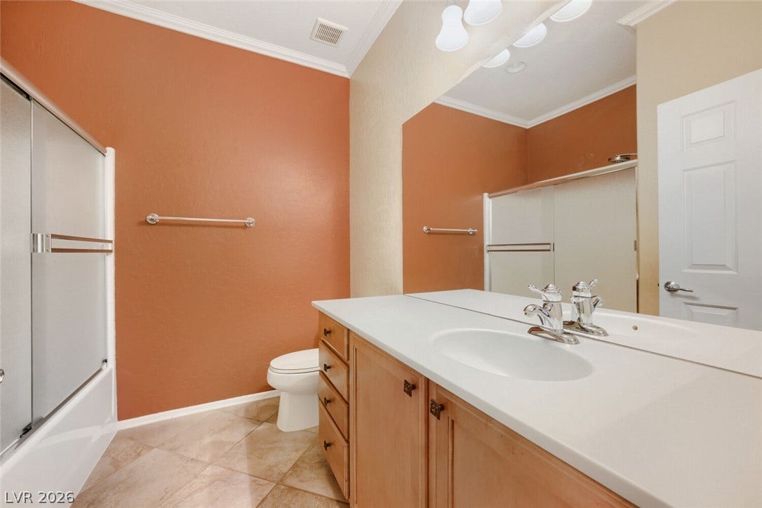 7421 Shelduck Street, North Las Vegas, NV 89084 Tiled floors and crown molding complement the vanity and large mirror in this bathroom.