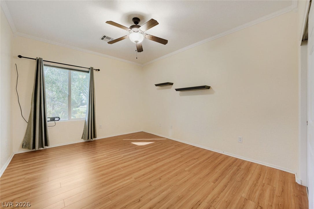7421 Shelduck Street, North Las Vegas, NV 89084 Warm wood flooring and clean crown molding enhance this versatile bedroom space.