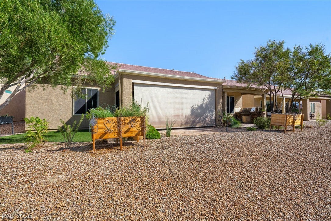 7421 Shelduck Street, North Las Vegas, NV 89084 Gravel landscaping frames the stucco exterior of this desert-style home with a covered back patio.