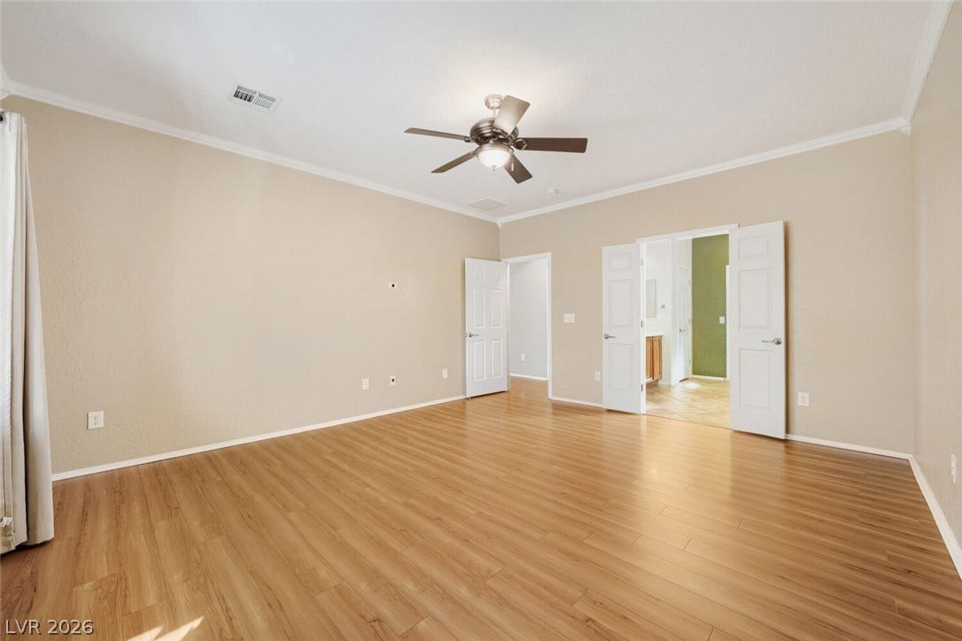 7421 Shelduck Street, North Las Vegas, NV 89084 Rich wood-inspired floors and smooth crown molding define this open, airy bedroom space.