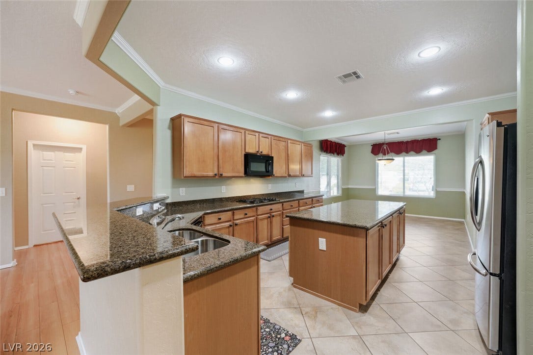 7421 Shelduck Street, North Las Vegas, NV 89084 Gleaming stone countertops and a spacious central island define this welcoming, tile-floored kitchen.