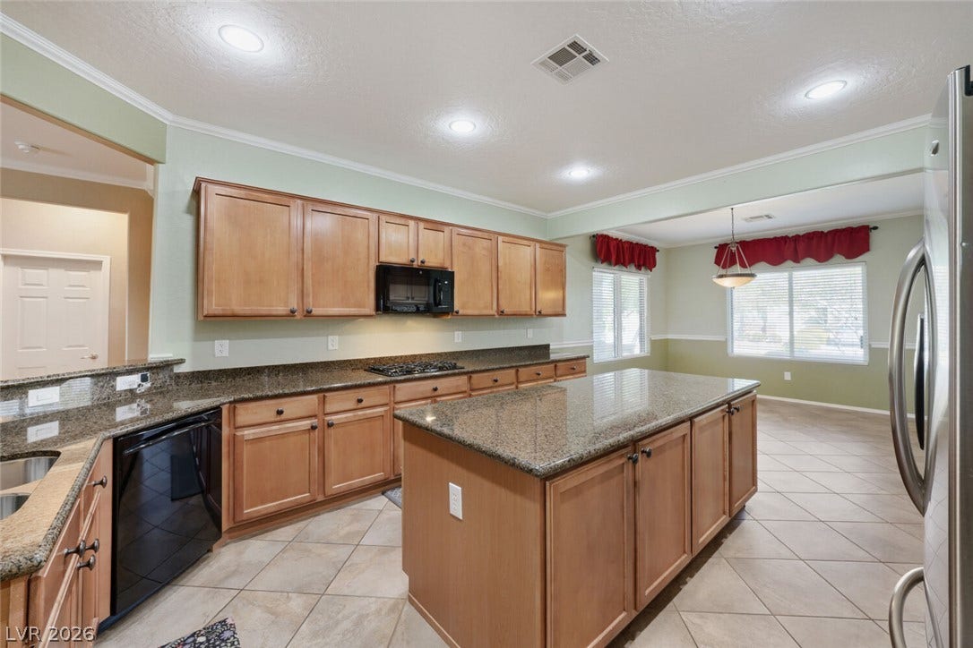 7421 Shelduck Street, North Las Vegas, NV 89084 Ample cabinetry and stone countertops anchor this central cooking space with diagonal tile flooring.