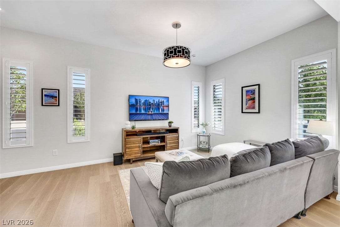 Hardwood floors and tall windows with plantation shutters accent this welcoming living space.