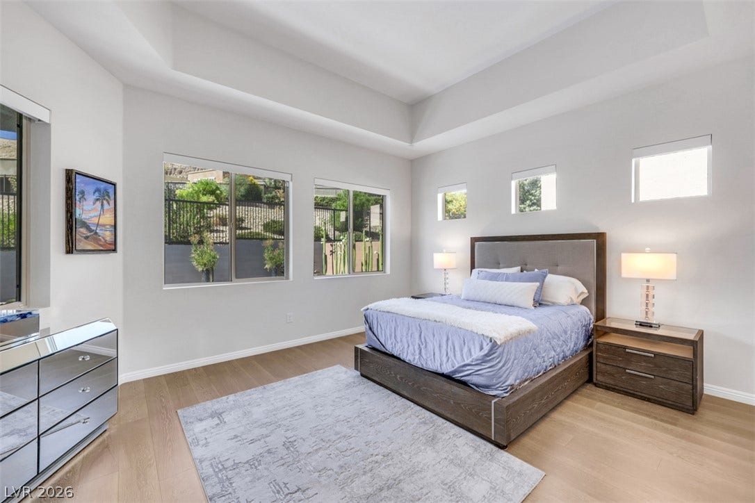 A serene primary suite is elevated by soaring ceilings and abundant natural light.