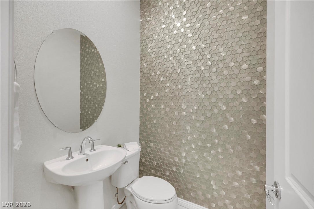 An elegant powder room showcases a pedestal sink alongside a textured accent wall.
