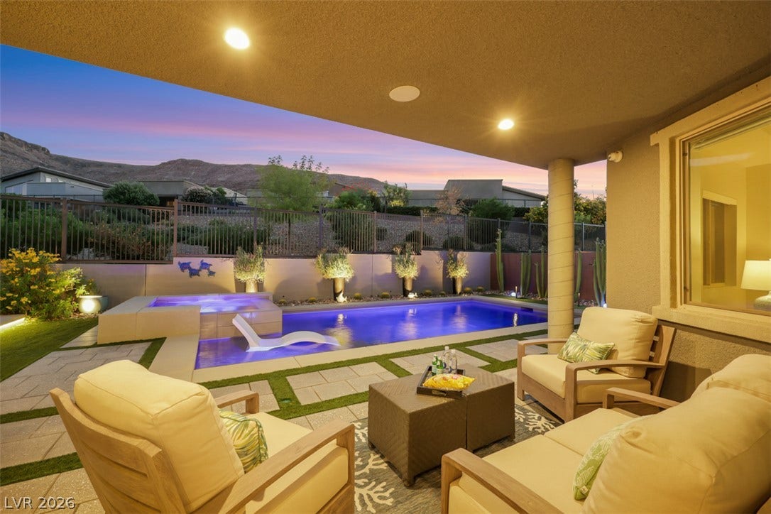 Covered outdoor living space overlooks a sparkling pool, framed by breathtaking desert mountains for an exceptional indoor-outdoor lifestyle.