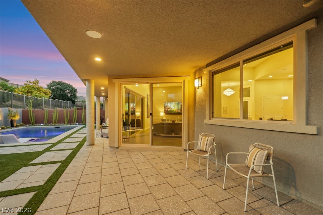 A spacious covered patio with tiled flooring overlooks the pool and backyard landscape.