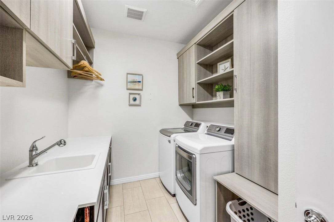 Elevated laundry space highlights custom cabinetry, abundant storage, a convenient utility sink and tile flooring.