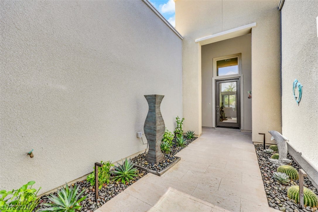 An elevated private courtyard welcomes you into the home with elegant stone pavers, a tranquil spa-inspired water feature and sophisticated desert landscaping.