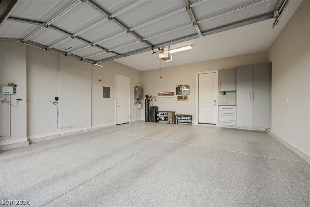 An organized garage features epoxy flooring alongside durable built-in cabinetry for streamlined home storage.