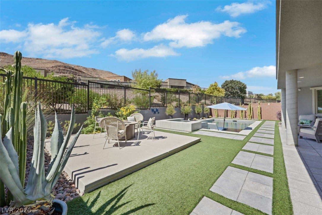 Backyard oasis features a swimming pool, elevated concrete patio areas, and scenic mountain views.