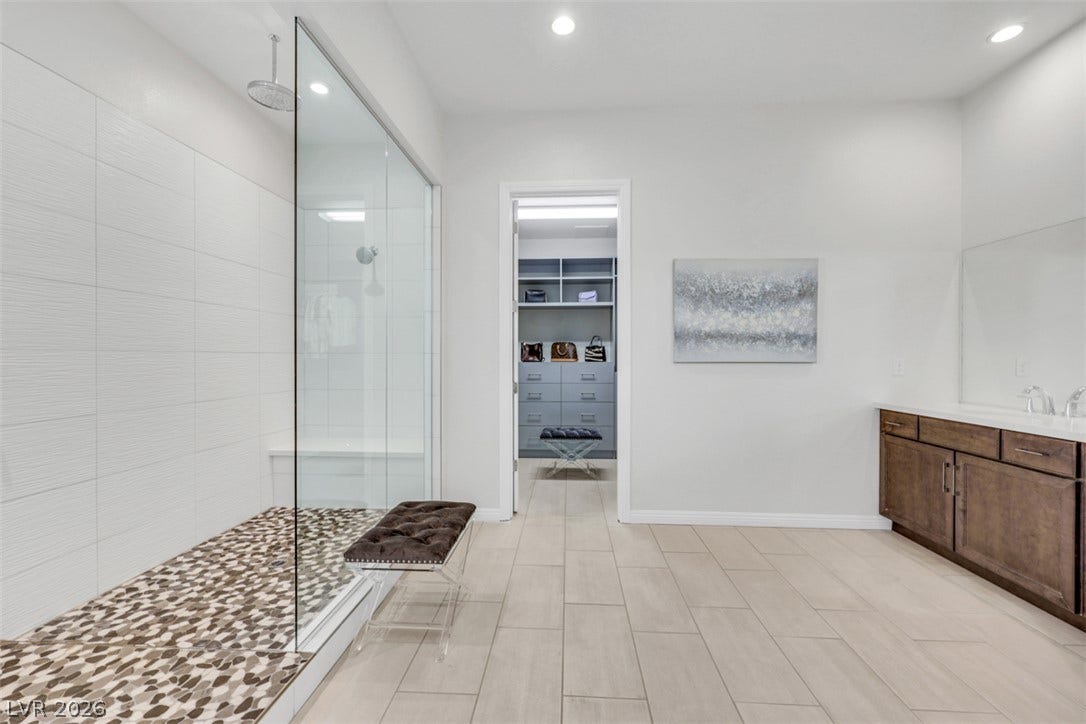 Expansive walk-in shower anchors this modern bath and expansive walk in closet offers abundant custom storage.