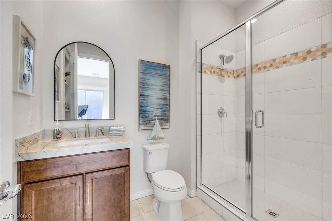Tiled walk-in shower and luxury stone-counter vanity highlight this modern bathroom space.