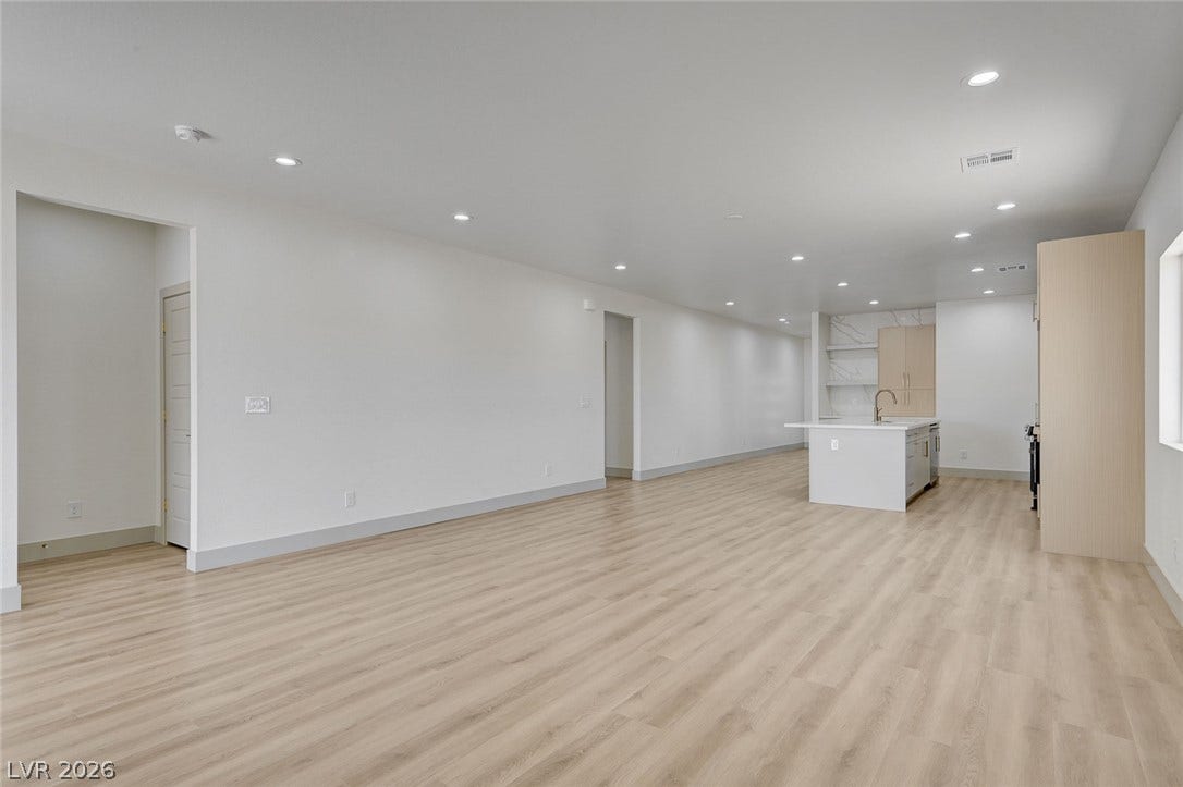 Recessed lighting illuminates this sprawling open layout transitioning seamlessly into the modern kitchen.