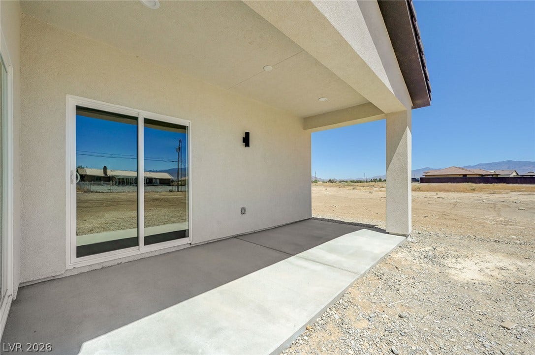 A covered concrete patio offers a shaded outdoor space looking out to desert views.