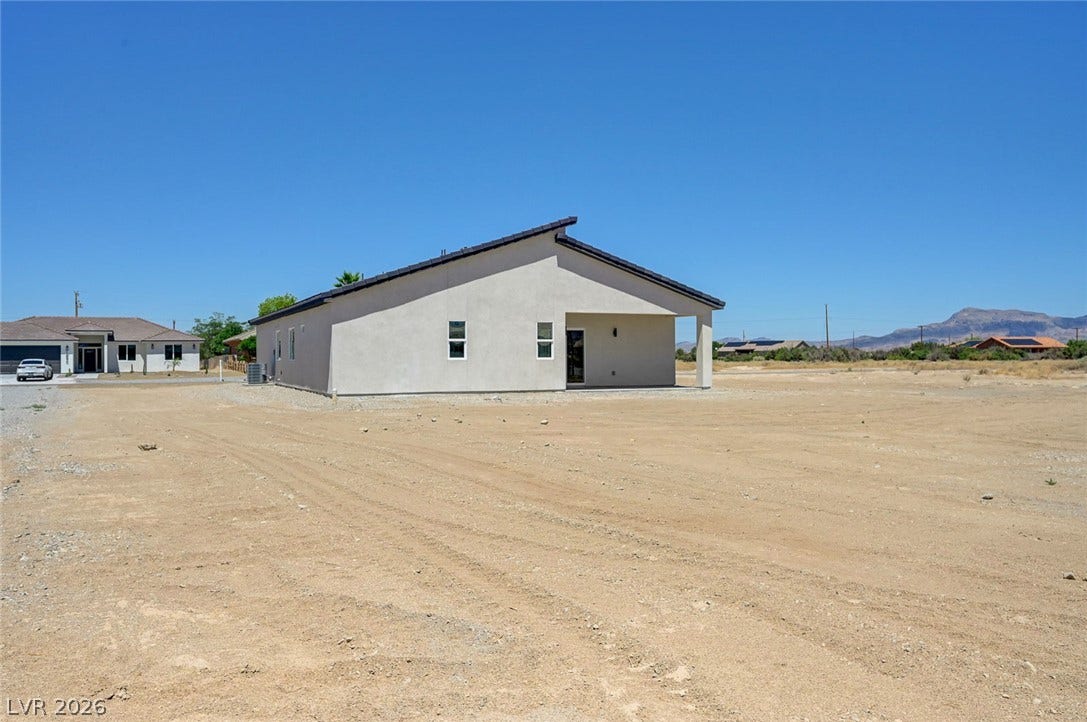 A stucco exterior frames this modern desert home with a covered back patio area.