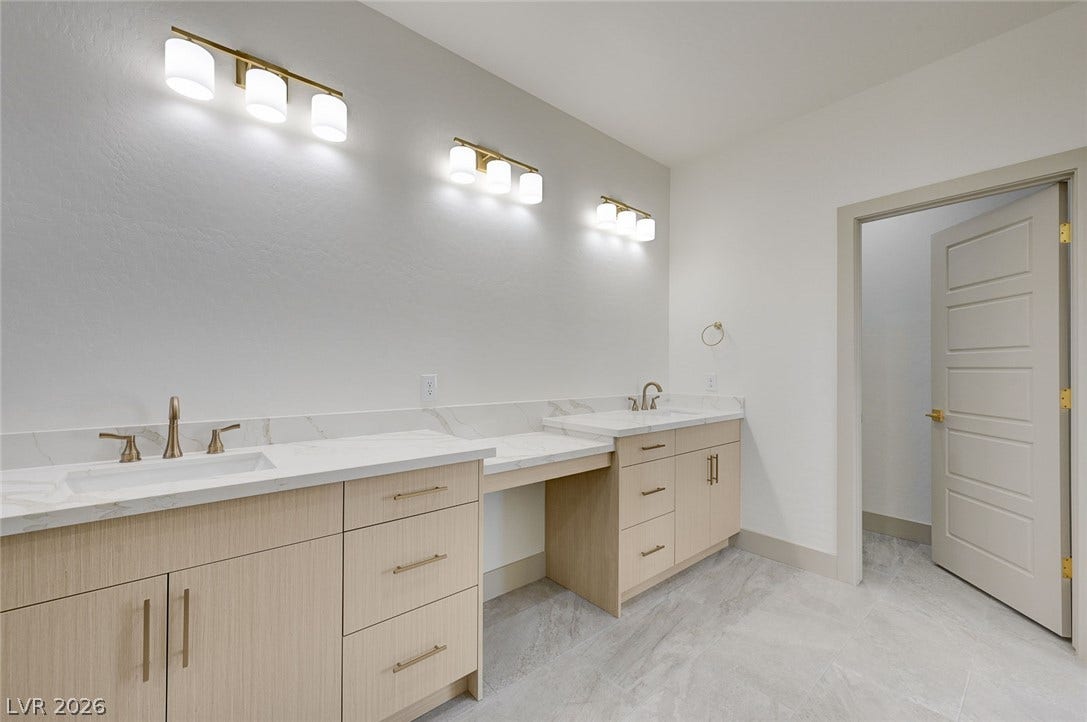 Clean lines and double vanities define this modern bathroom with neutral tile flooring.
