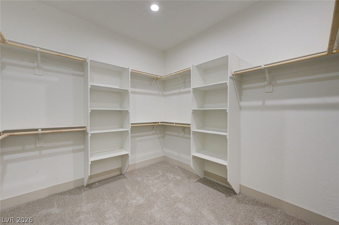 Generous built-in shelving and hanging rods maximize storage within this carpeted closet.
