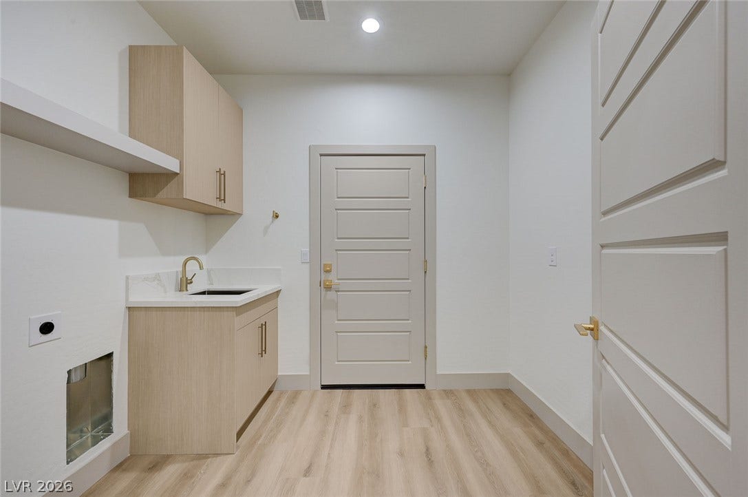 Functional utility space features modern cabinetry alongside wood-look flooring and clean white walls.