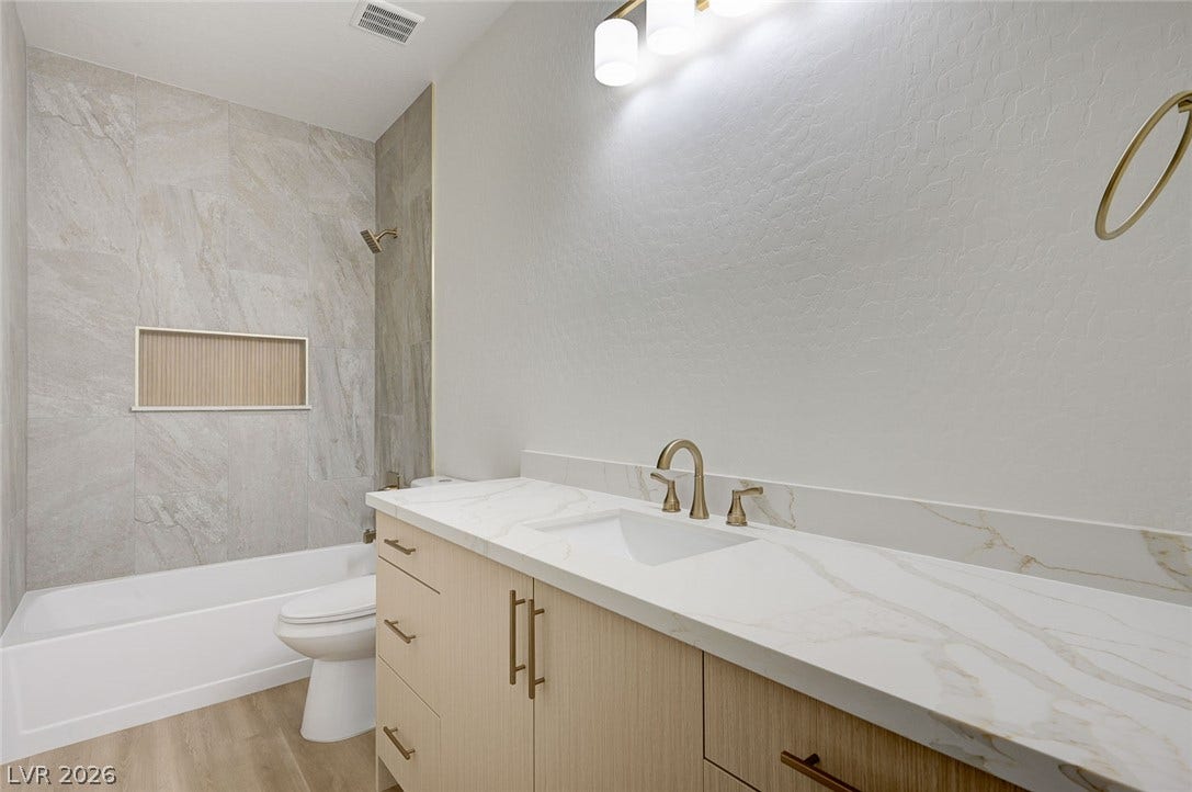 Fine stonework surrounds the tub alongside a modern vanity under warm overhead lighting.