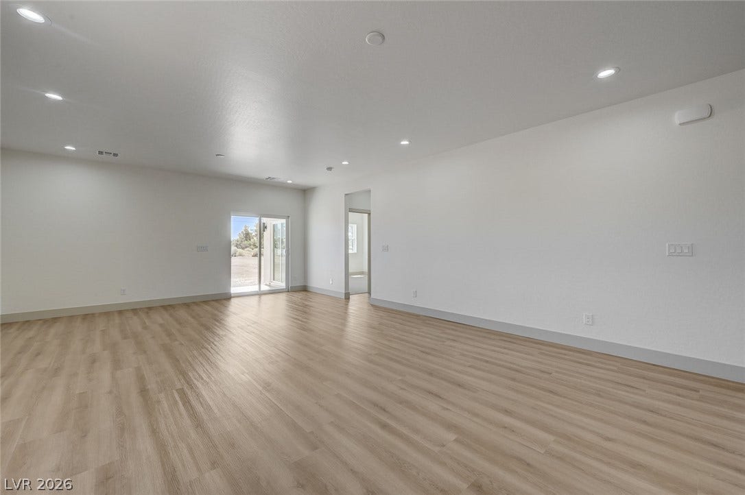 Recessed lighting illuminates this versatile open living space anchored by warm wood-look flooring.