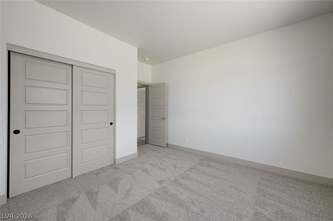Plush carpeting underfoot complements the clean lines and neutral walls of this versatile bedroom.