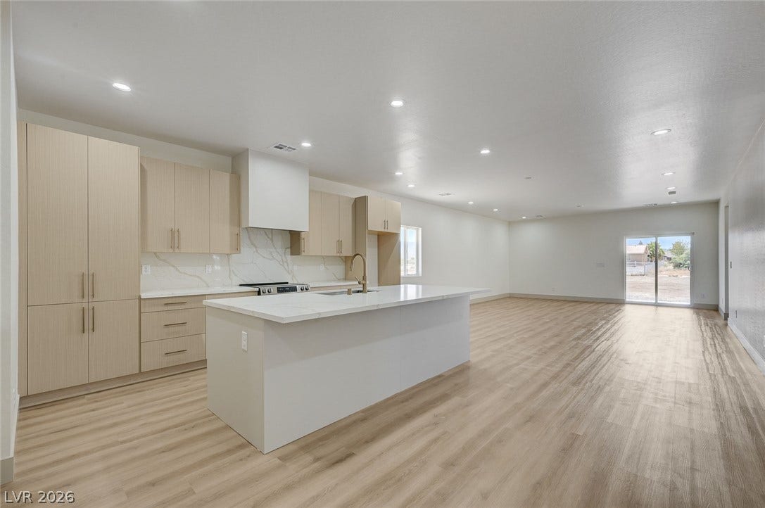 An open-concept living area flows seamlessly into a kitchen featuring a central stone-topped island.