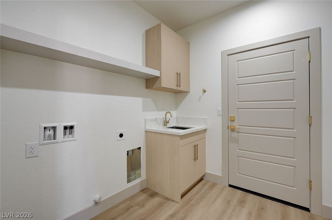 A functional utility space features wood flooring, built-in cabinetry, and a convenient sink setup.