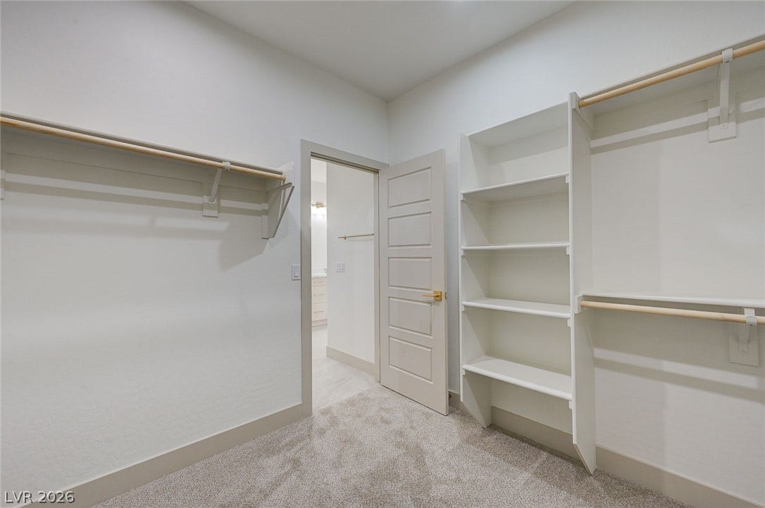 Ample built-in shelving and hanging rods define this organized storage space with plush carpeting.