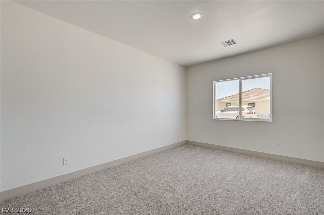 Plush carpeting and a wide window define this versatile secondary bedroom space.