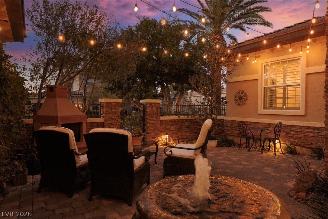 9795 Amador Ranch Avenue, Las Vegas, NV 89149 An inviting stone-paved courtyard features a warming outdoor fireplace under twilight skies.