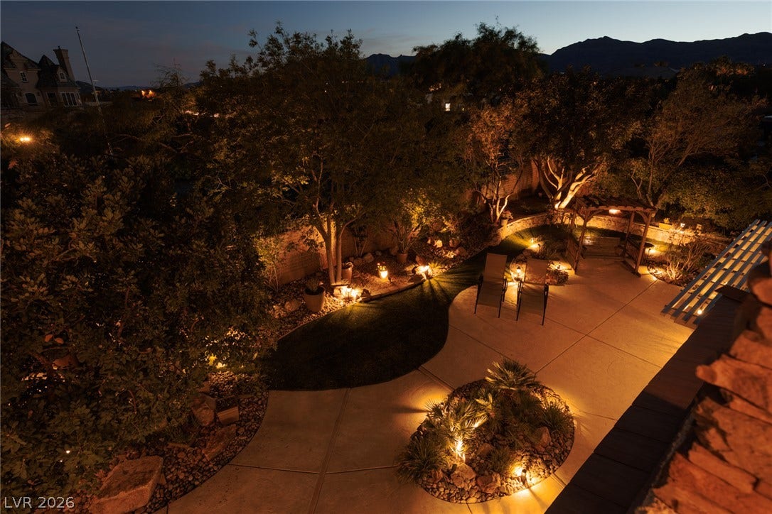 9795 Amador Ranch Avenue, Las Vegas, NV 89149 Thoughtful landscape lighting illuminates the paved patio, curved pathways, and mature garden beds.