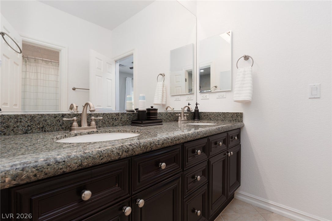 9795 Amador Ranch Avenue, Las Vegas, NV 89149 Granite countertops and dark cabinetry elevate this bathroom with timeless texture.