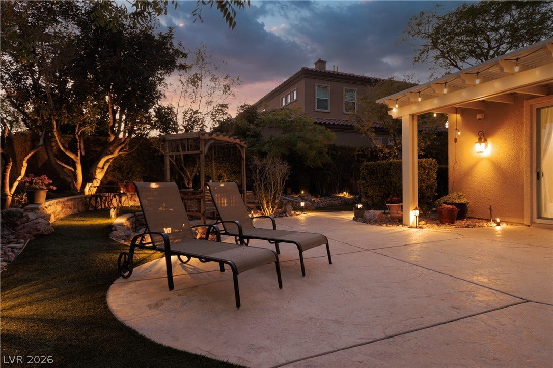 9795 Amador Ranch Avenue, Las Vegas, NV 89149 An inviting backyard patio area seamlessly connects to landscaped grounds under a twilight sky.