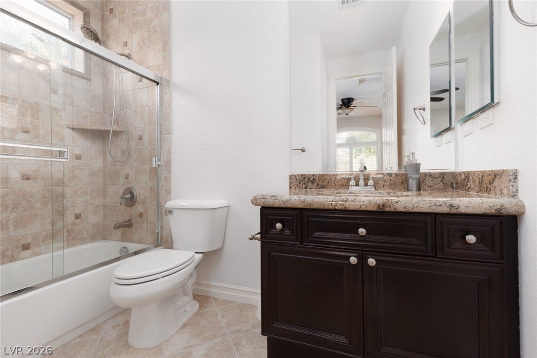 9795 Amador Ranch Avenue, Las Vegas, NV 89149 Rich granite countertops pair with a tiled tub shower combination in this secondary bath.
