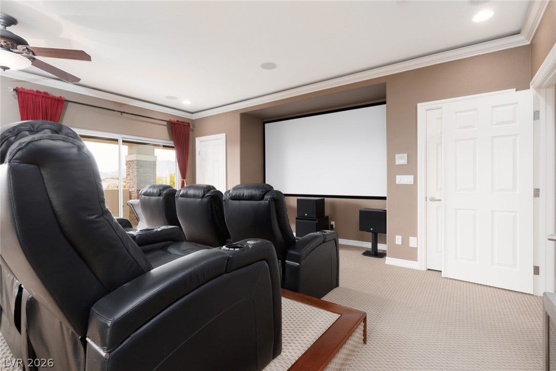 9795 Amador Ranch Avenue, Las Vegas, NV 89149 Crown molding and glass sliding doors enhance this dedicated home entertainment space with carpeted flooring.