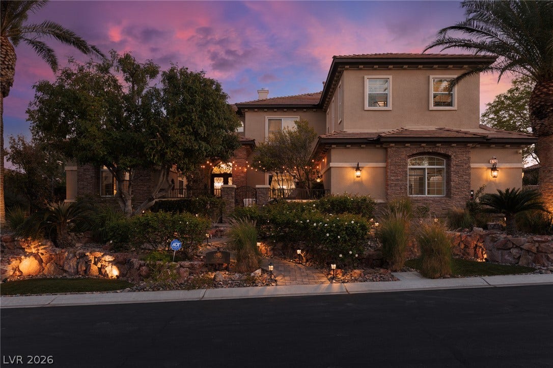 9795 Amador Ranch Avenue, Las Vegas, NV 89149 Lush landscaping and stone accents frame this elegant two-story residence under a twilight sky.